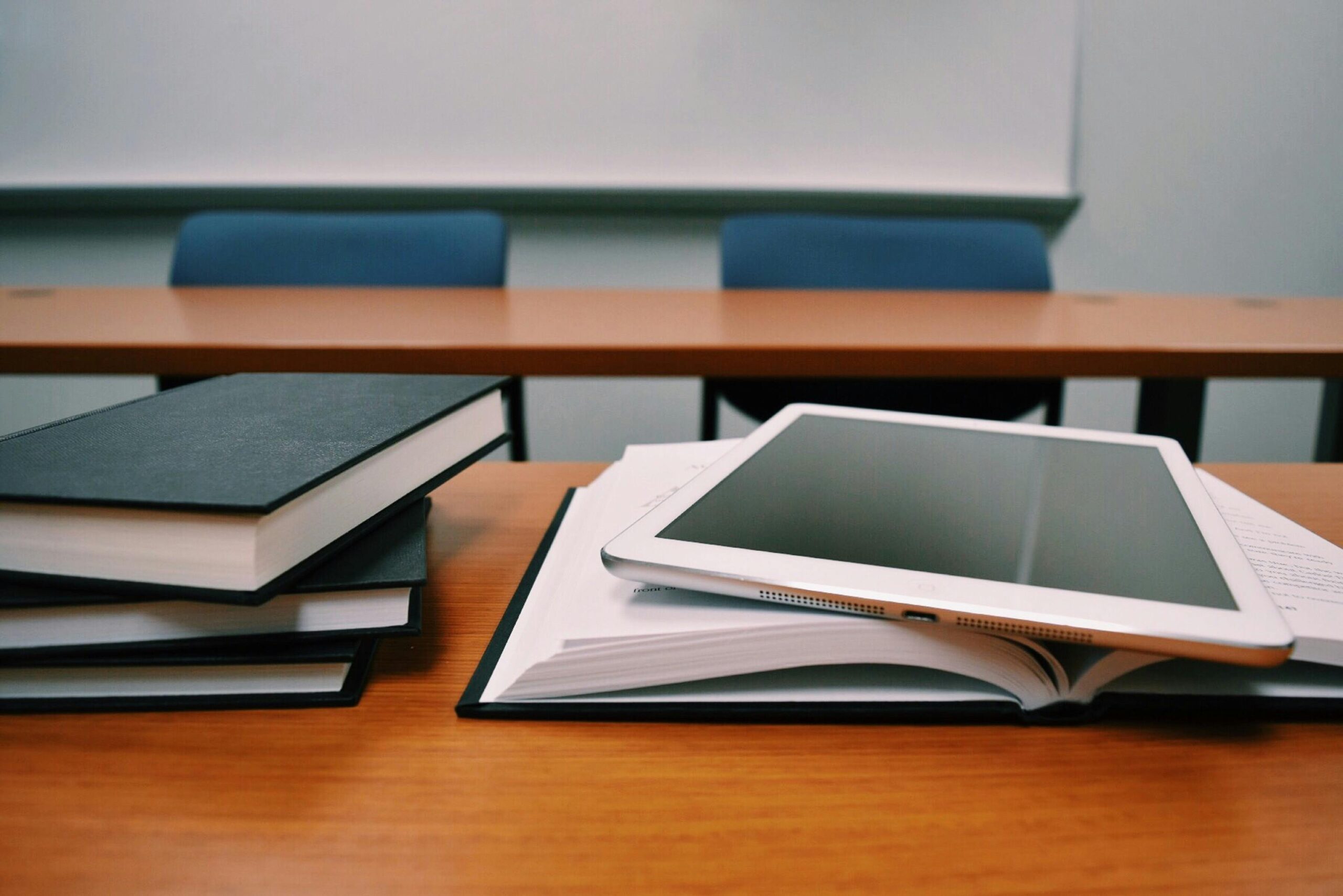 A collection of books and a tablet on a table. Photo by: Pixels.com.